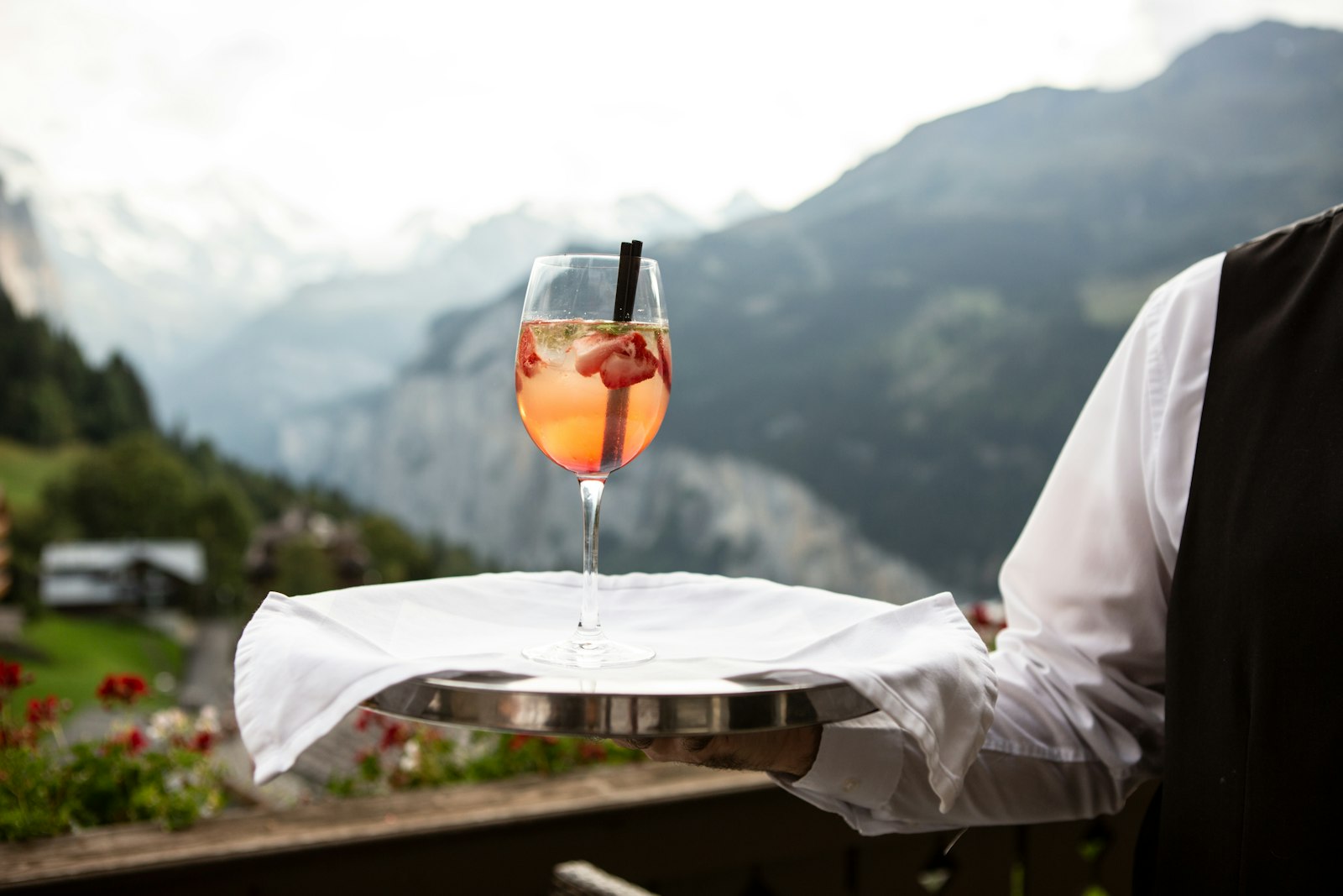 Waiter presenting a drink against an alpine view