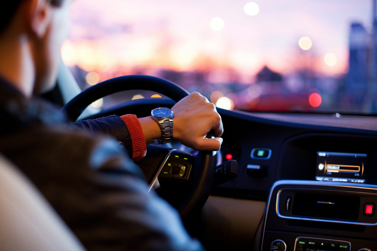 Chauffeur driving through city lights at dusk