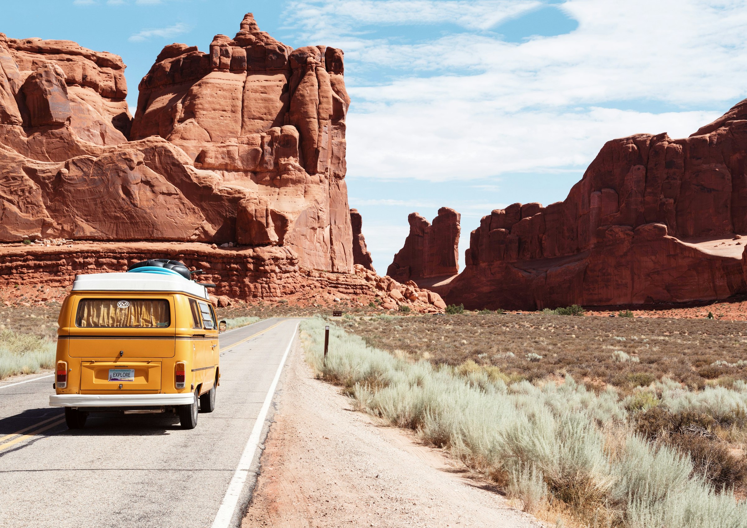 Vintage van driving a desert road between red canyons