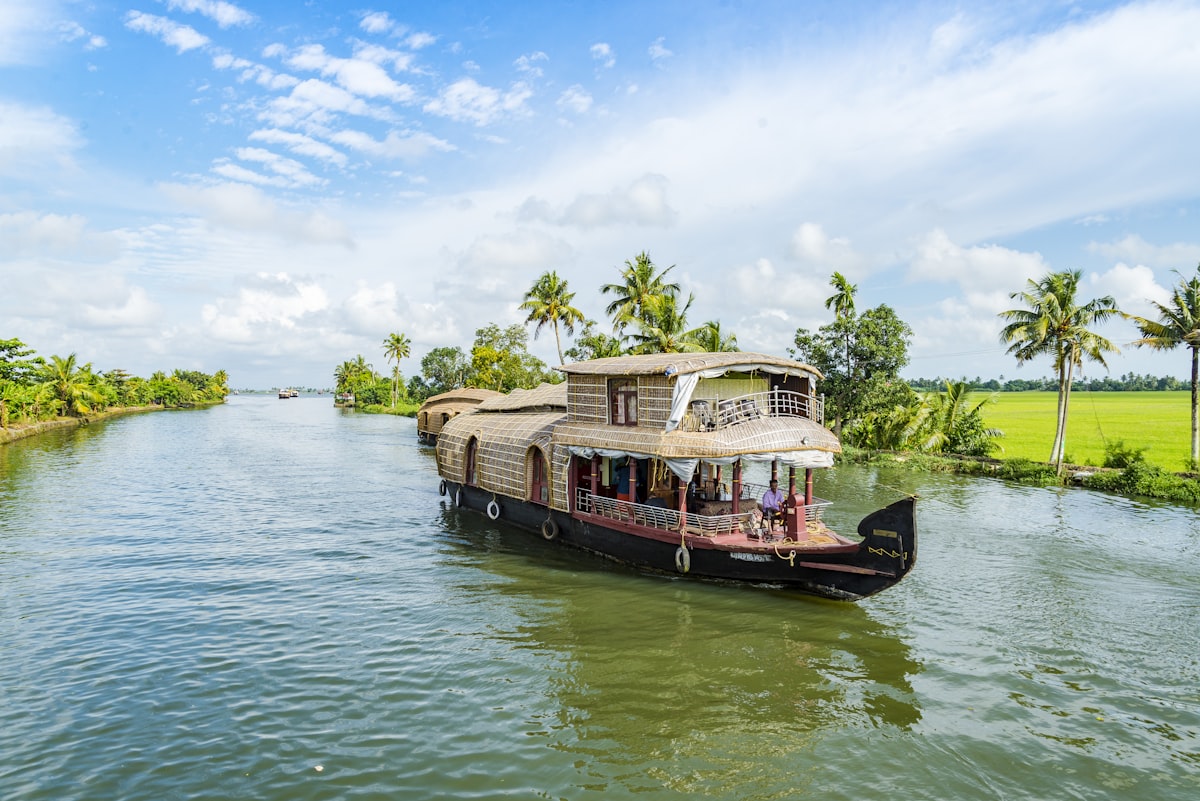 Houseboat cruising Kerala backwaters past paddy fields