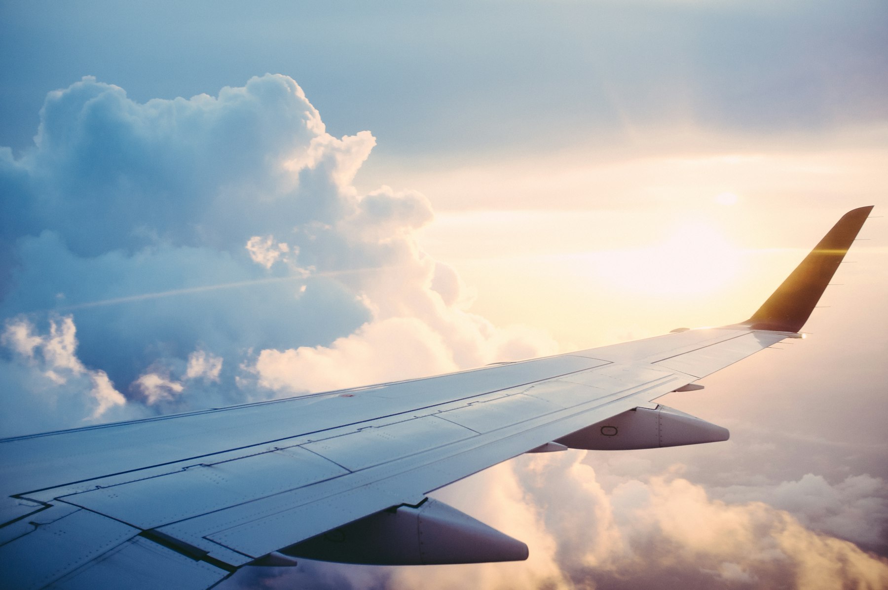 Aircraft wing above golden evening clouds